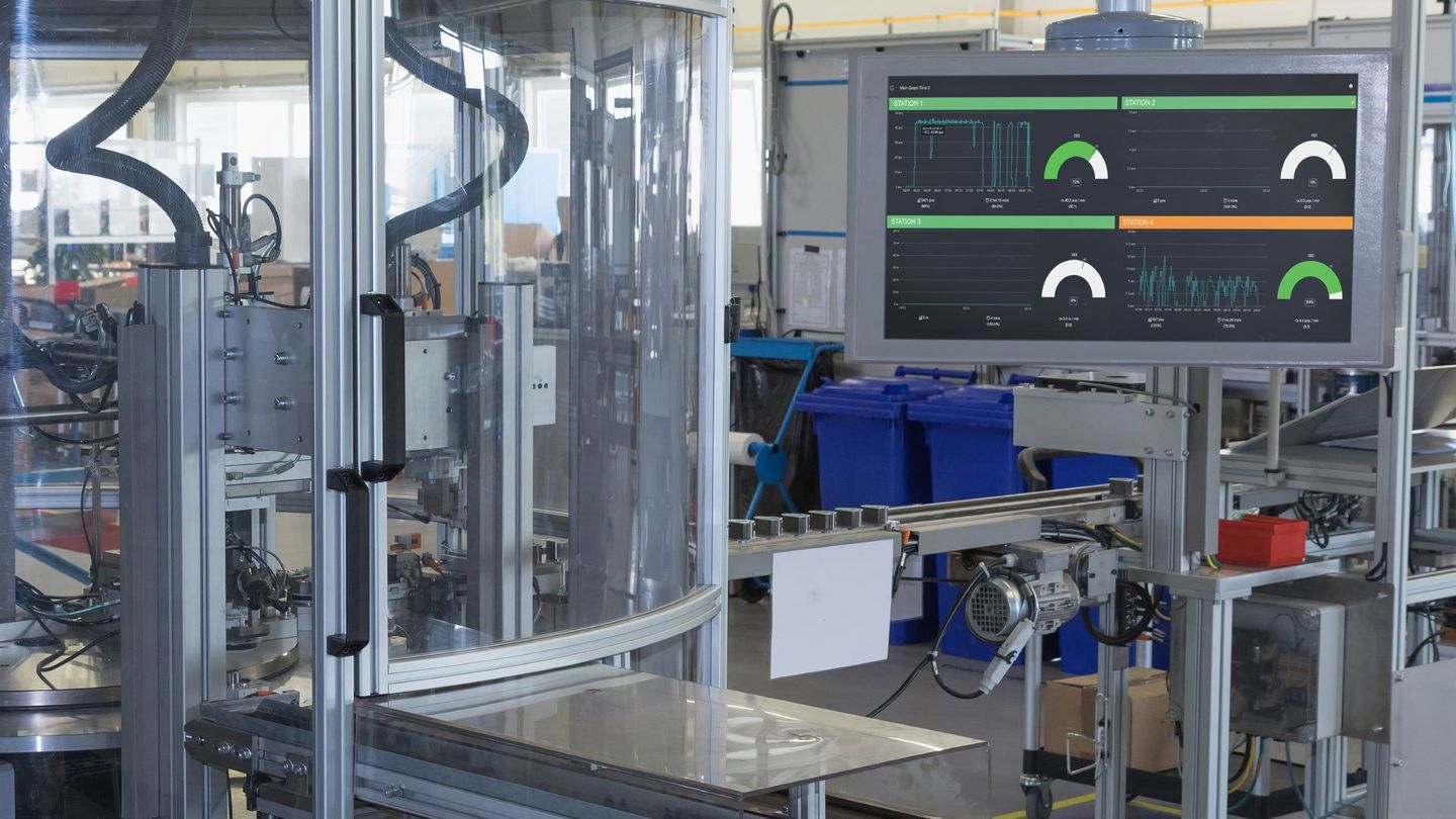Industrial machinery with a large digital monitor displaying graphs and gauges in a factory setting.